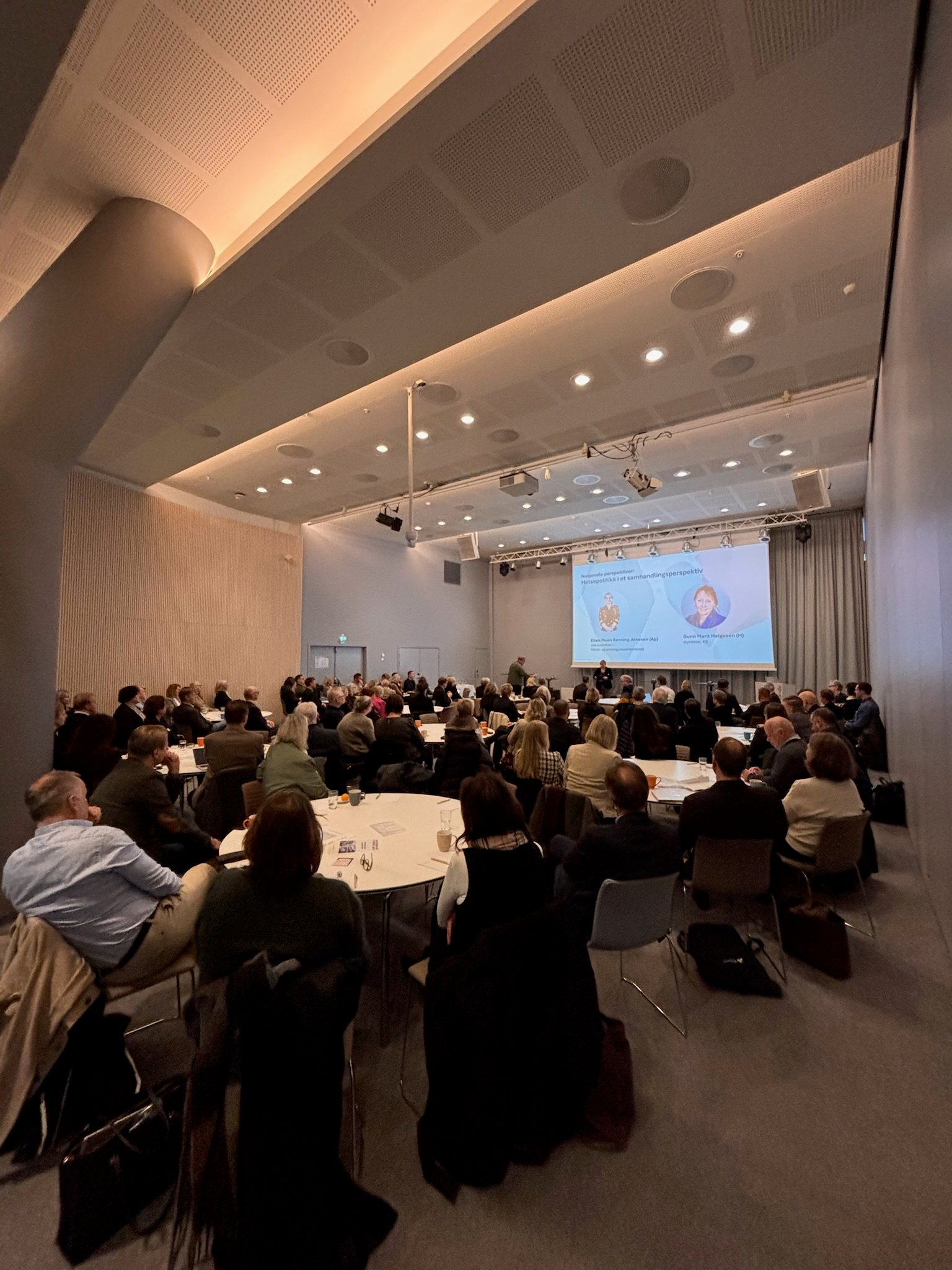 En gruppe mennesker som sitter i et rom og ser på en skjerm