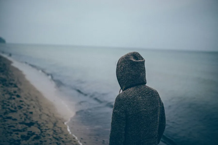 En person som står på en strand og ser ut på havet